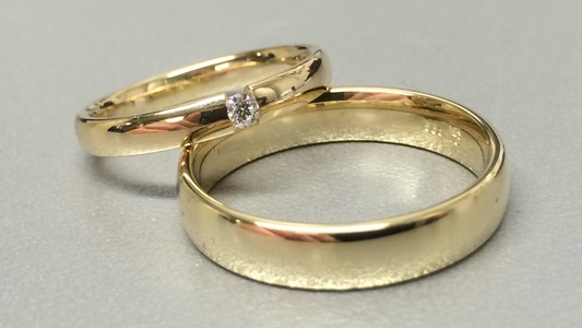 Gelbgoldene Trauringe, schlicht, der eine Ring mit einem einzelnen Stein