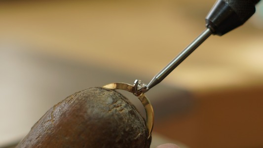 Der Prozess des Steinefassens an einem Ring mit einer Krappenfassung.